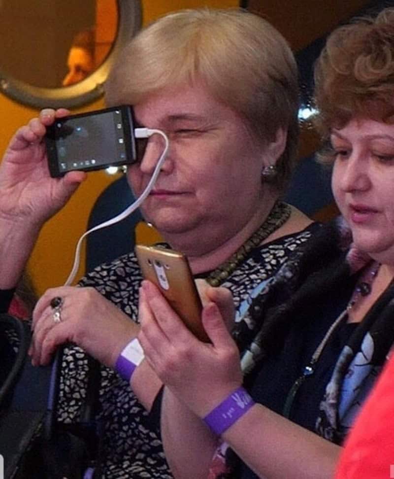 Two women taking photos with their phones, one with a camera, in a social setting.