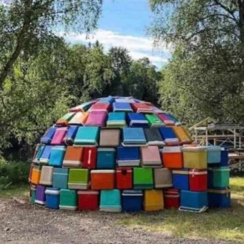 Colorful stack of suitcases arranged in a dome shape outdoors.