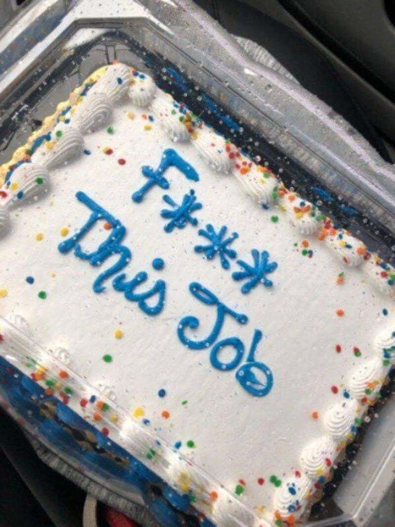 Cake with blue writing 'F*** This Job' and colorful sprinkles on white frosting.