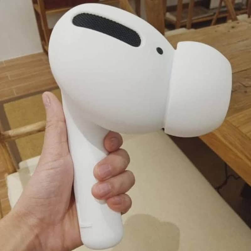 Hand holding a white hairdryer shaped like a dog's head.