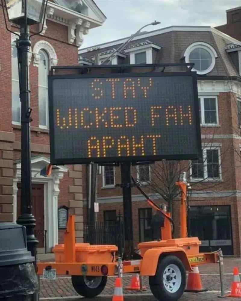 Sign reads 'STAY WICKED FUN AHEAD' in a city street.