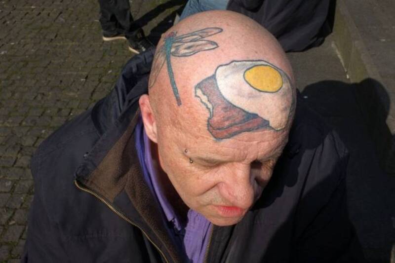 Bald man with a tattoo of a fried egg on his head.