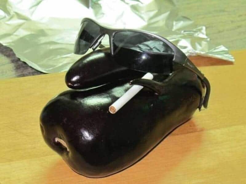 A black object resembling a piggy bank with sunglasses and a cigarette on top.
