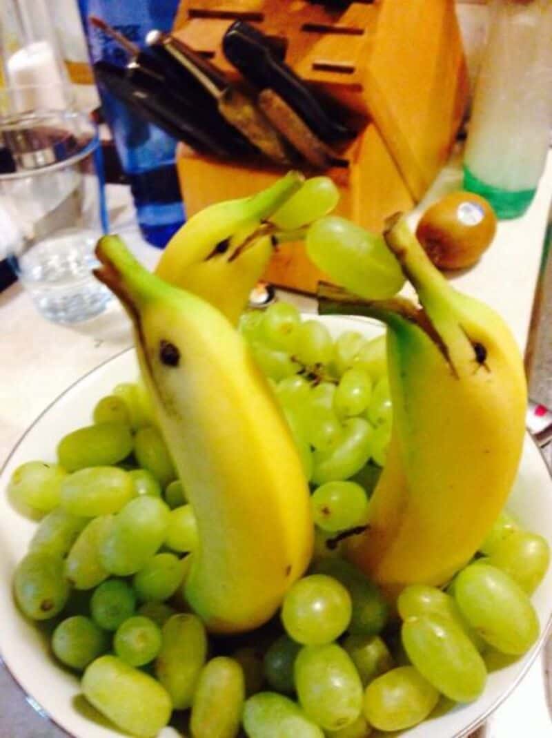 Bananas and grapes arranged to look like a face with a hat.