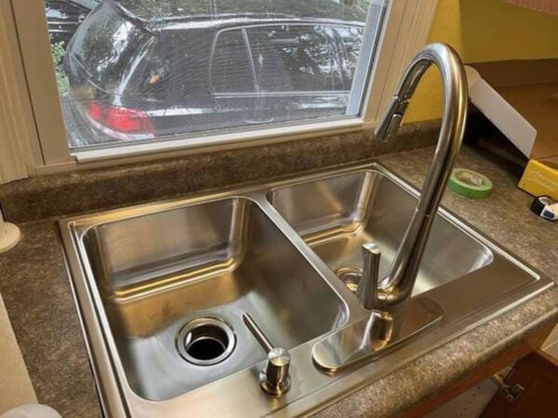 Double kitchen sink with a single faucet and a window above it.