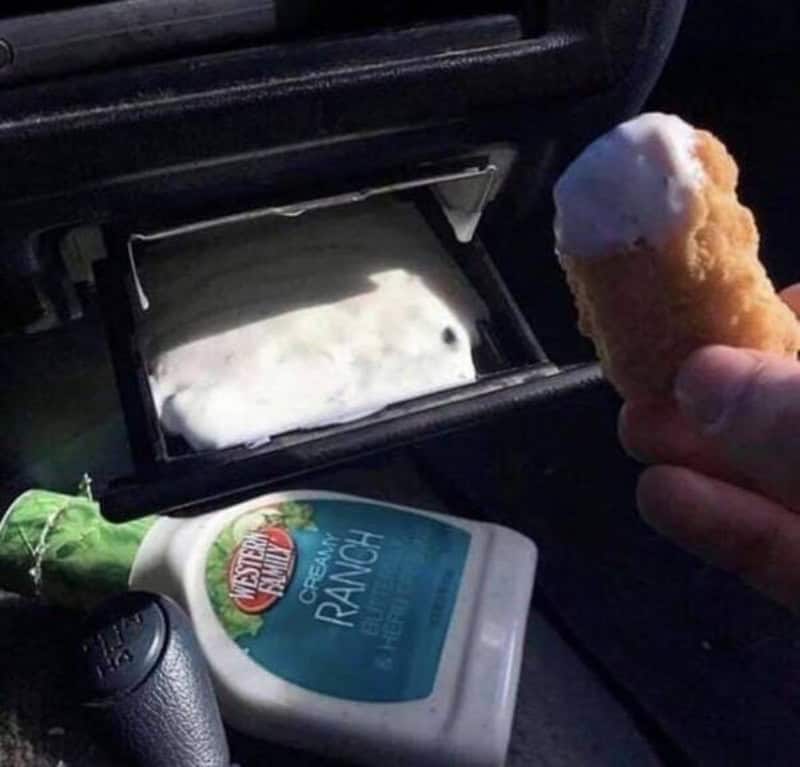 Ice cream cone held near a car's open glove compartment with ranch dressing inside.