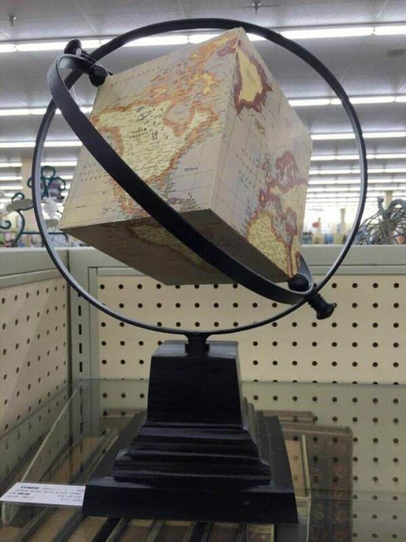 A globe with a cube-shaped world map on a black stand.