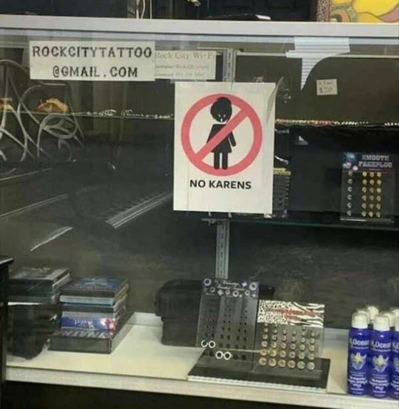 Sign says 'No Karens' with a crossed-out cartoon girl figure.