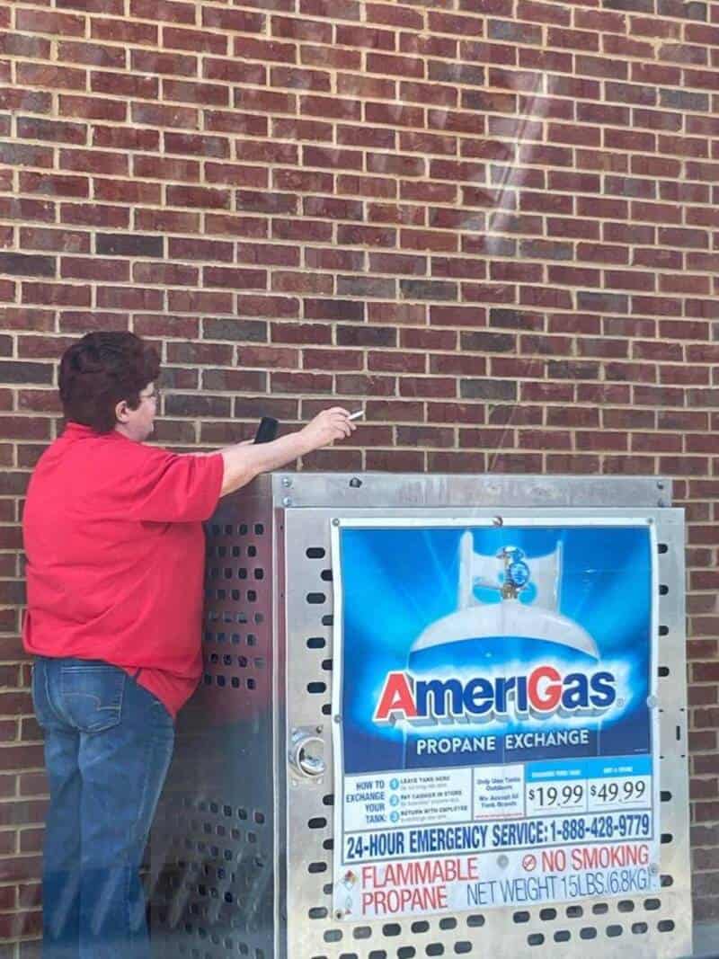 Child in red shirt reaching for a gas valve on an AmeriGas propane exchange tank.