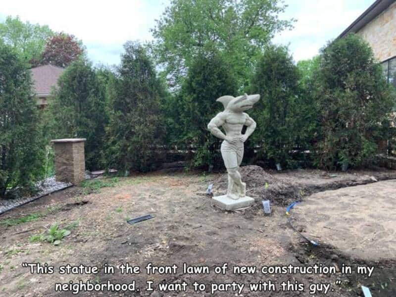 Statue of a person with a crocodile head in a backyard, with text about a new construction.