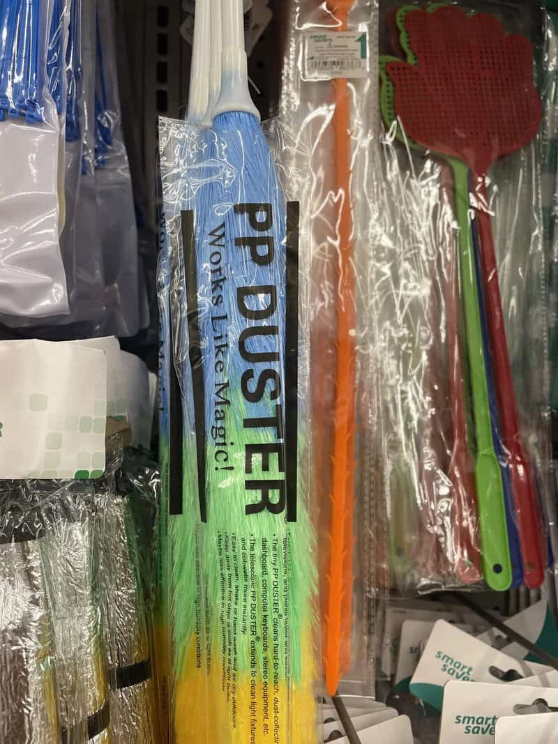 Colorful plastic utensils and a blue cleaning cloth on a store shelf.