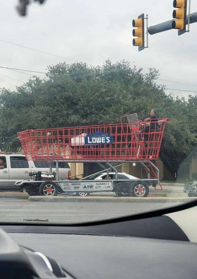 Shopping cart on a car with Lowe's sign, at a traffic light.