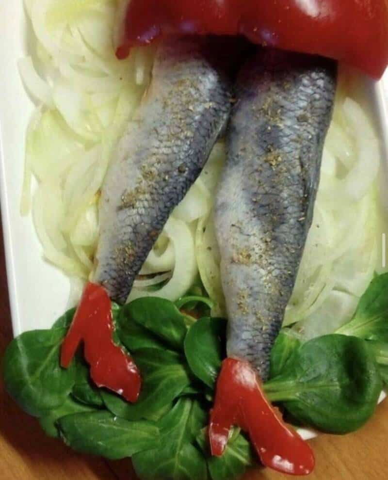 Fish legs with red chili peppers as shoes on a bed of vegetables.