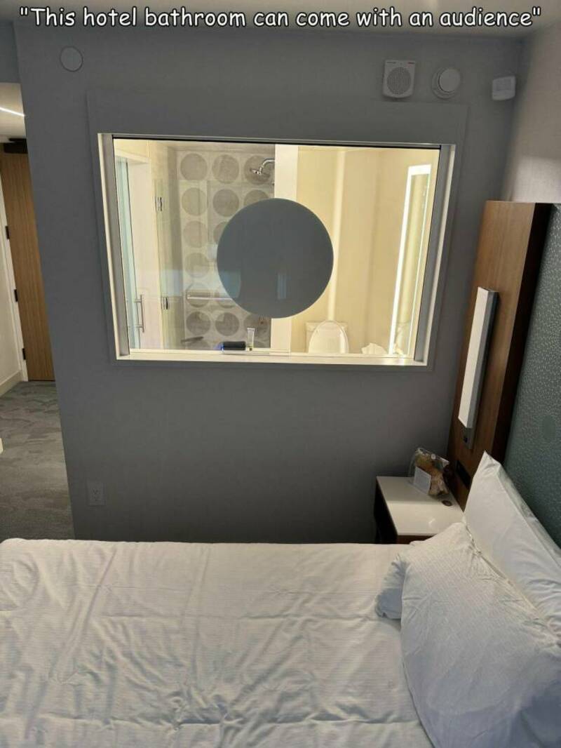 Hotel bathroom seen through a window with a round mirror and a quote at the top.