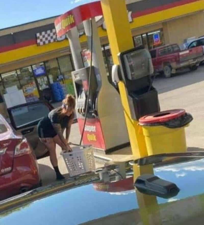 Woman at gas station bending down to pick up a basket.