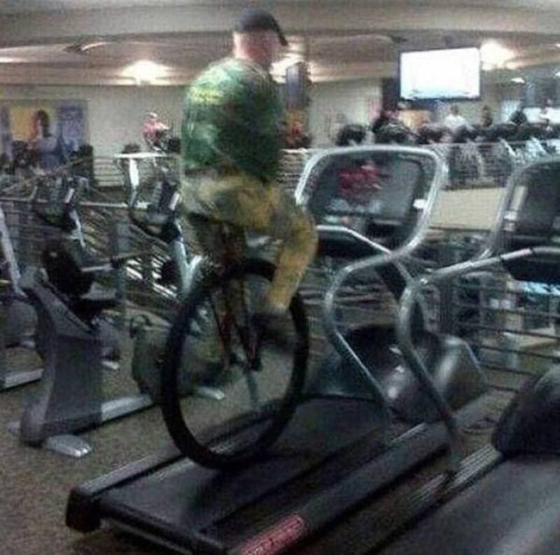 Man riding a bicycle on a treadmill in a gym.
