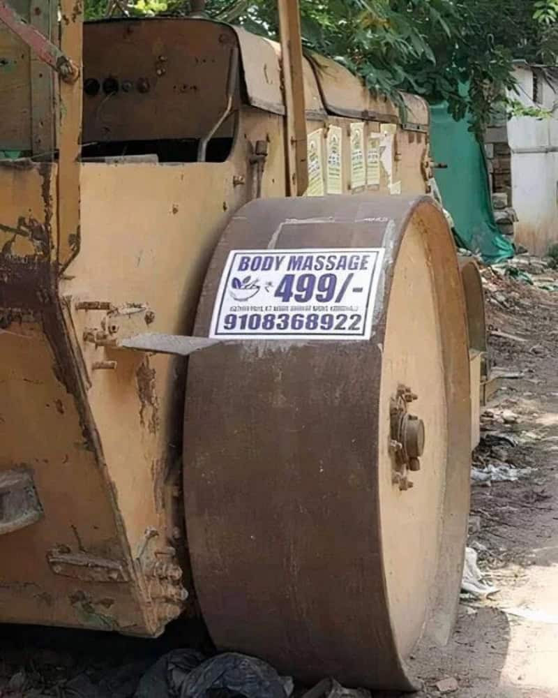 Body massage sign on a large, rusty wheel attached to an old vehicle.