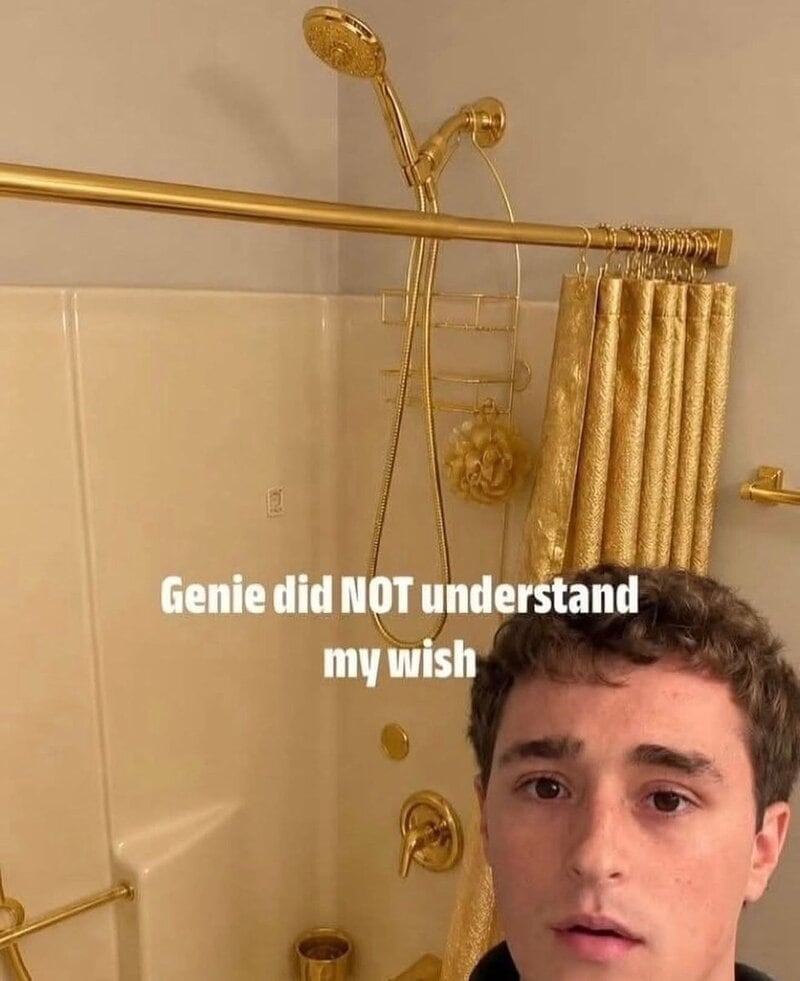 Young man with a surprised expression in a bathroom with gold fixtures and shower curtain.