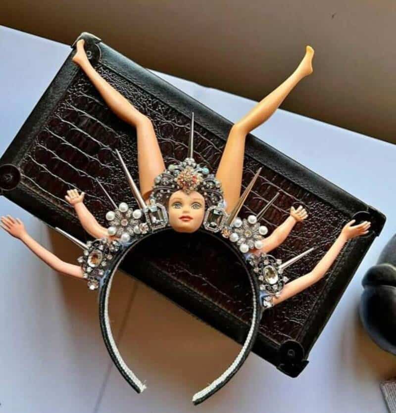 A doll with multiple arms and a jeweled headpiece on a black box.