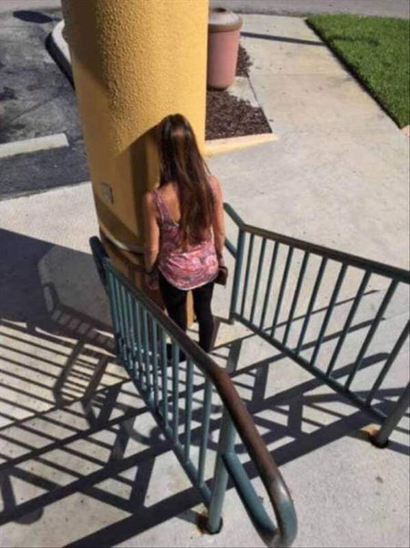 Woman with long hair standing at the top of stairs near a yellow wall.