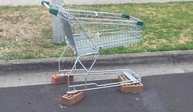 Shopping cart on bricks blocking a parking space.