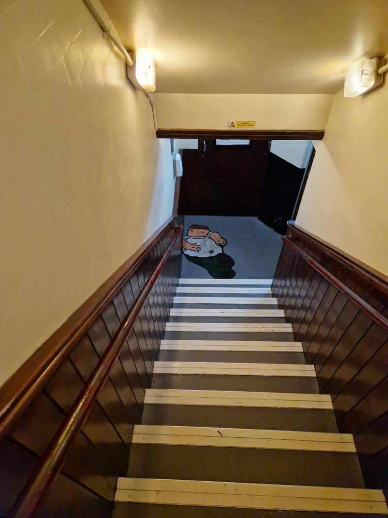 Staircase leading down to a door with a cartoon character on the floor.