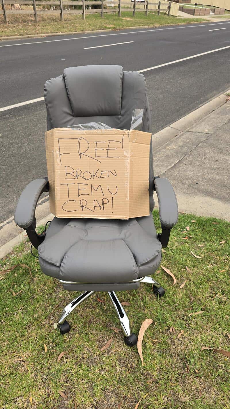 Office chair with a cardboard sign saying 'FREE! BROKEN TEMU CRAP!'.