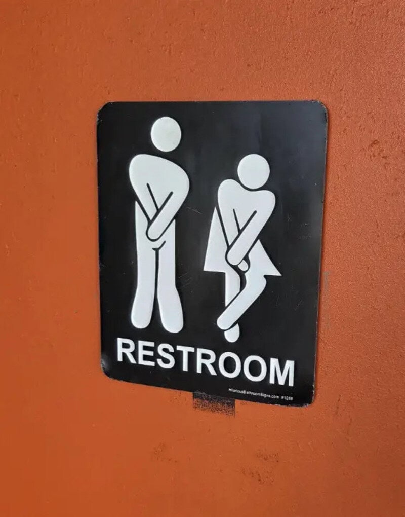 Restroom sign with a humorous depiction of a man and woman.