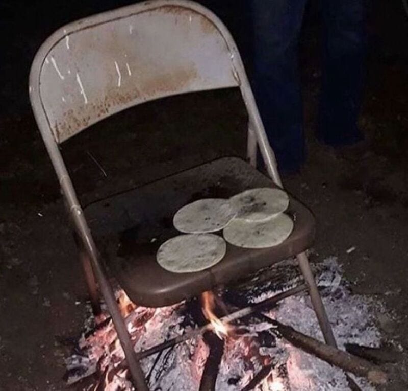 Chair with three stones on it over a fire pit, in a dark setting.