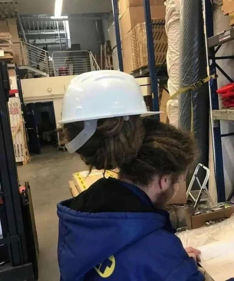 Person wearing a white safety helmet working in a warehouse.