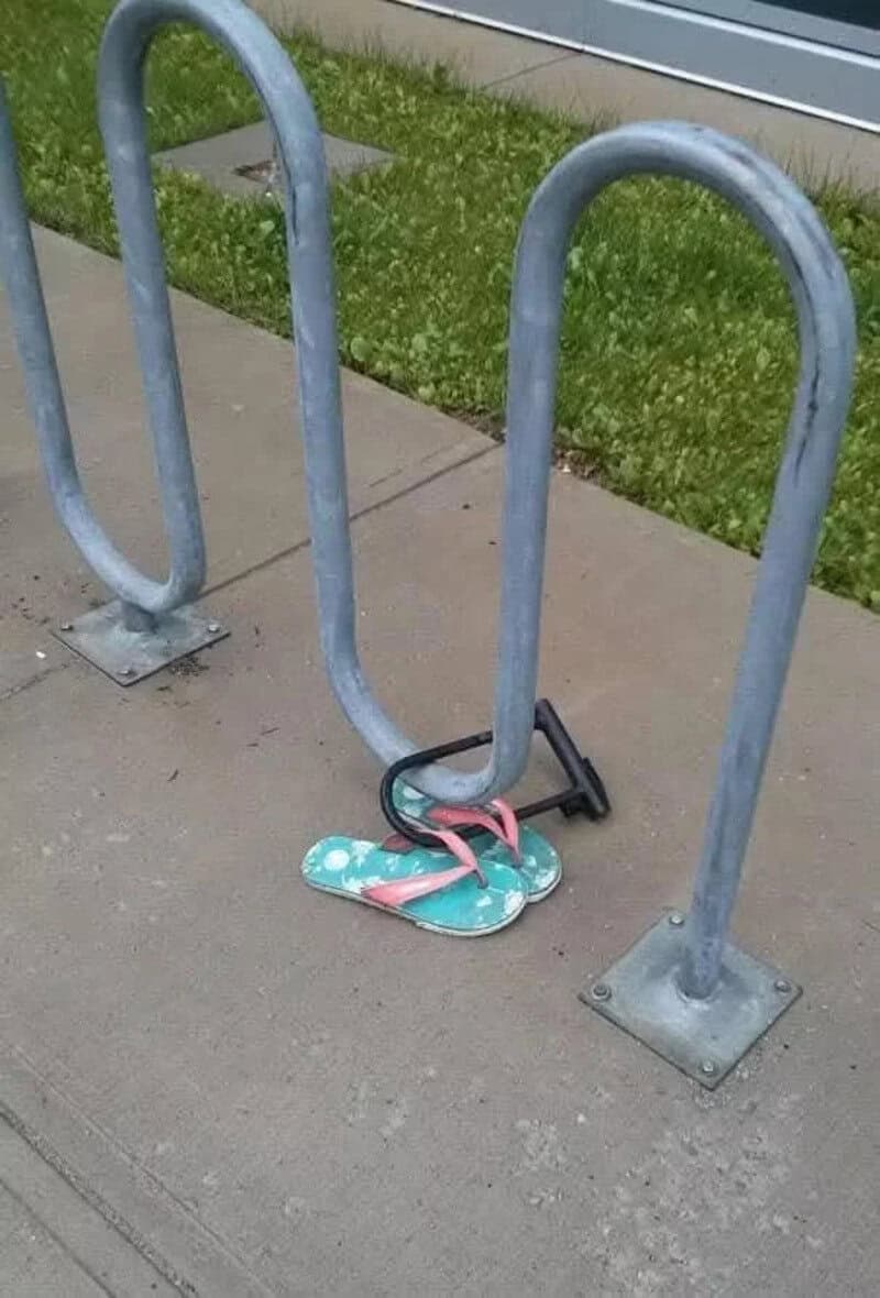 Flip-flops caught in bike rack on sidewalk.