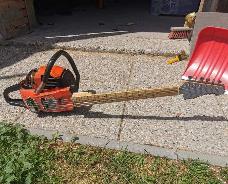 A chainsaw with a guitar neck attached, resembling a guitar.