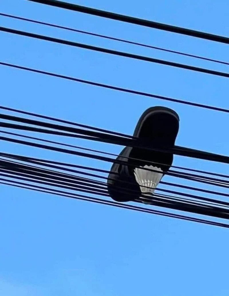 Streetlight caught in power lines against blue sky.