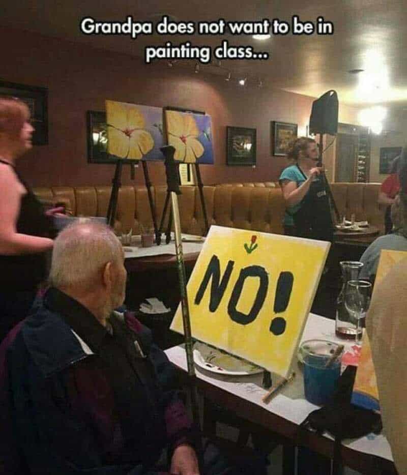 Grandpa in painting class with a 'NO!' sign in front of him.