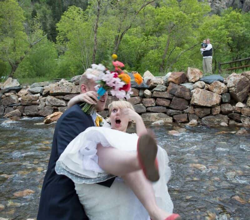 Bride and groom in a river, the bride wearing a flower crown, the groom holding her.