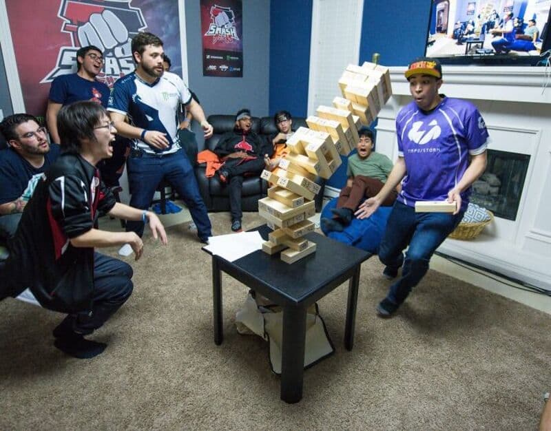 Group of people watching a Jenga tower fall during a game.