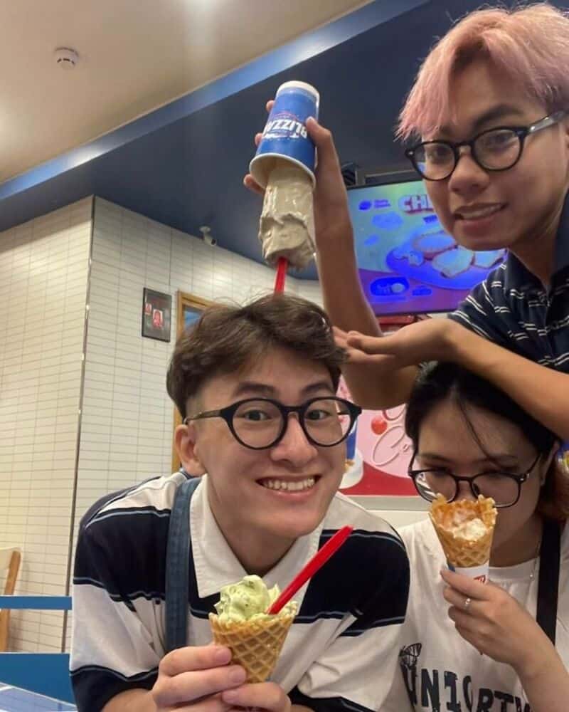 Three friends with ice cream cones, one holding a humorous ice cream hat.