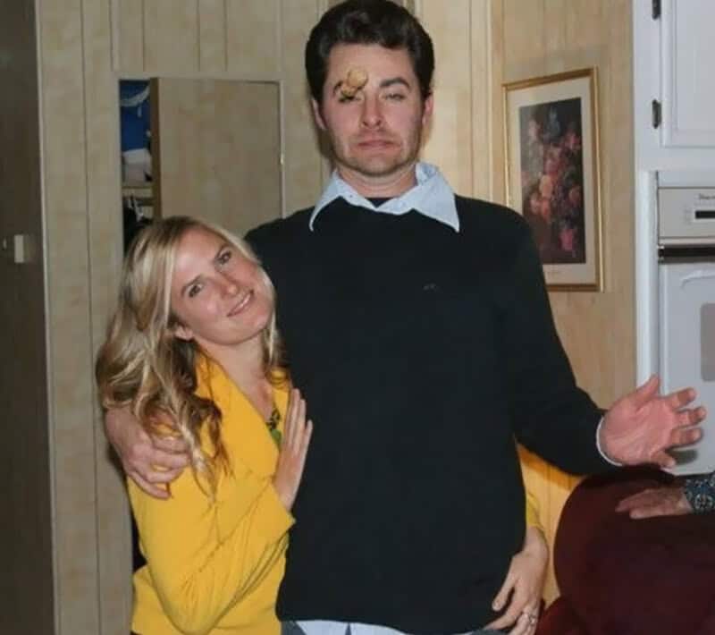 A woman with blonde hair in a yellow top and a man with a bandage on his forehead pose together.