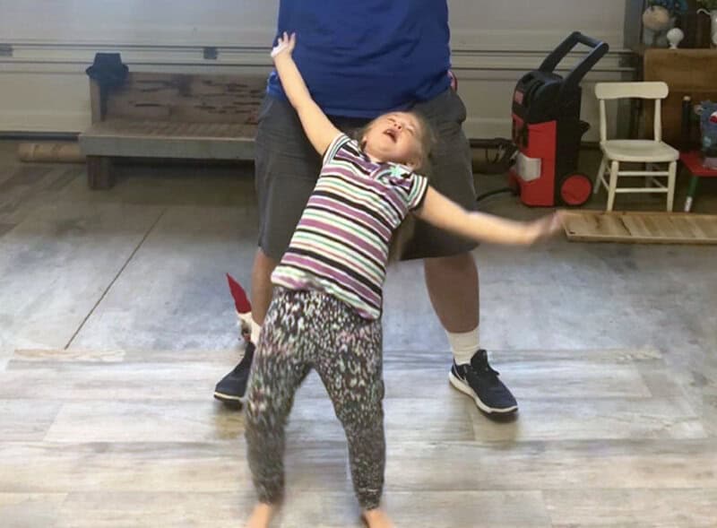 Child falling backward with arms outstretched in a playful pose.