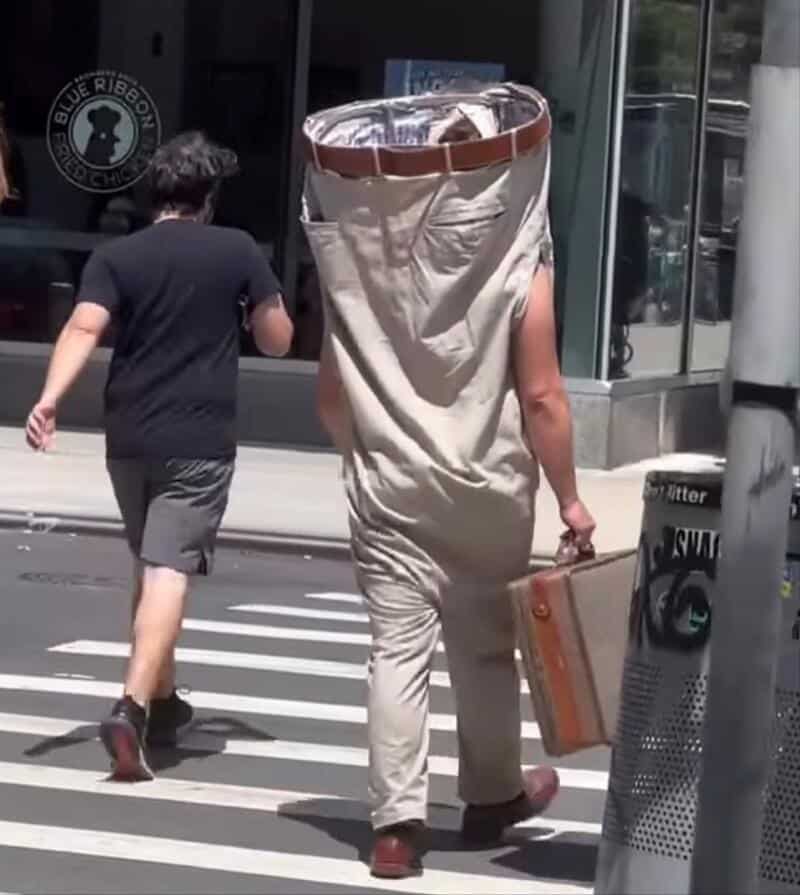 Person dressed as a giant coffee cup walking on city street with another person.