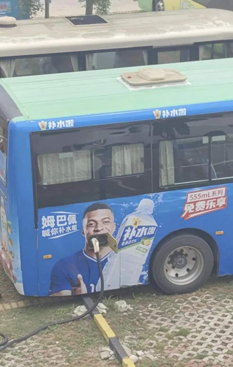 Electric bus with advertisement featuring a man and a water bottle.