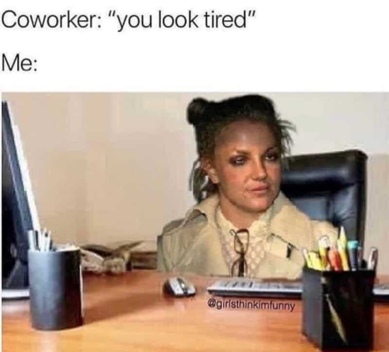 Woman at desk with tired expression, office supplies around her.