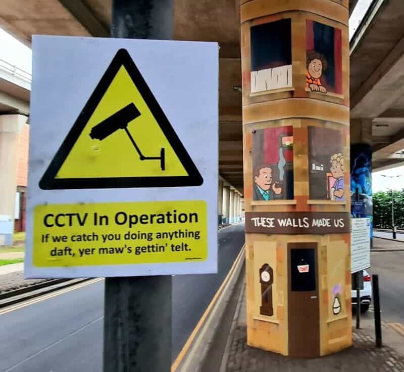 CCTV sign warning about surveillance and a mural on a pillar with children and a sign saying 'These墙.