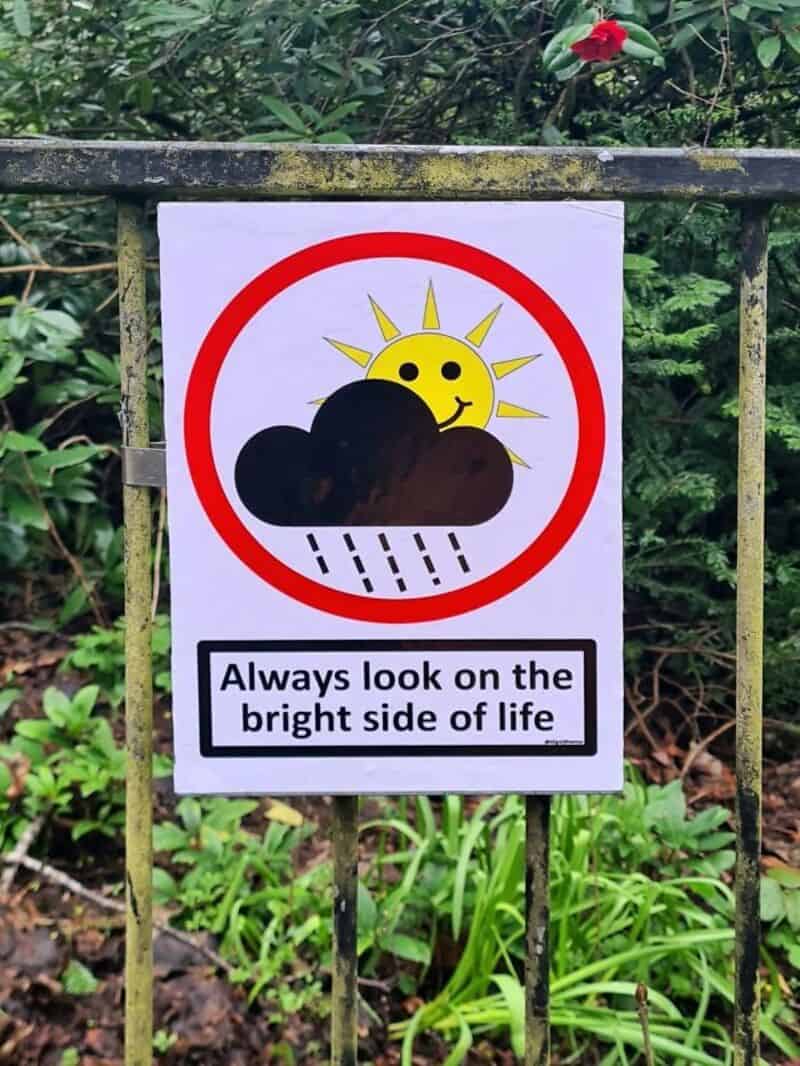 Sign with a sun, cloud, and rain, saying 'Always look on the bright side of life'.