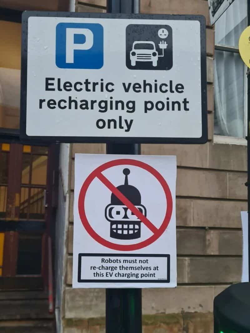 Electric vehicle recharging point only with a no robot sign below.