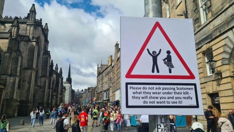 Warning sign with humorous message about passing Scotsmen and their kilts.