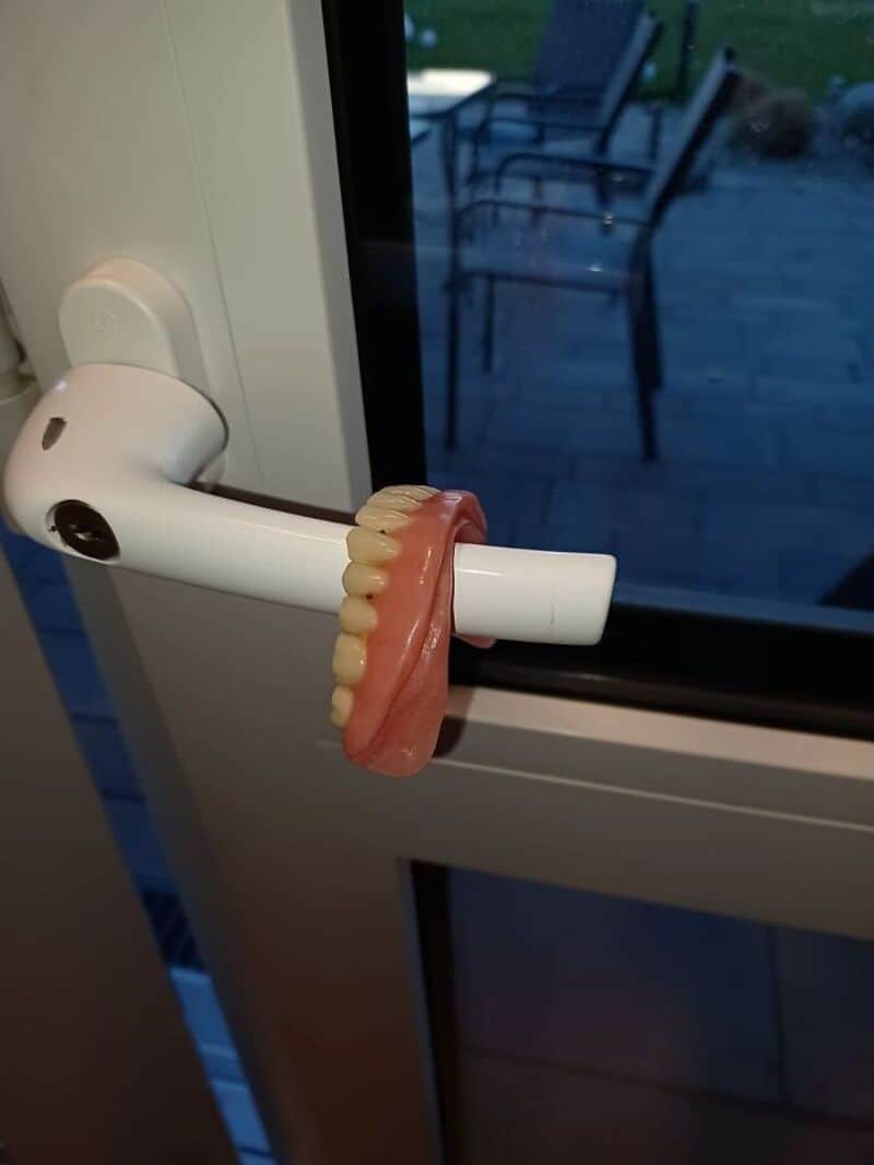 Toothbrush holder with a fake set of teeth on a door handle.