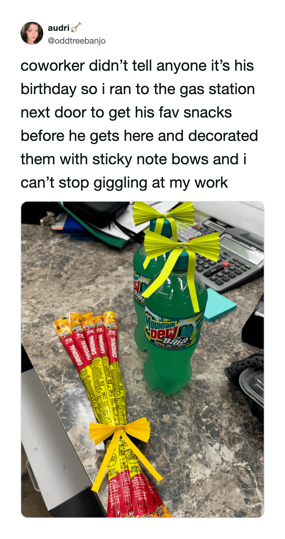 A soda bottle with a green bow and two packs of snacks with yellow bows on a desk.