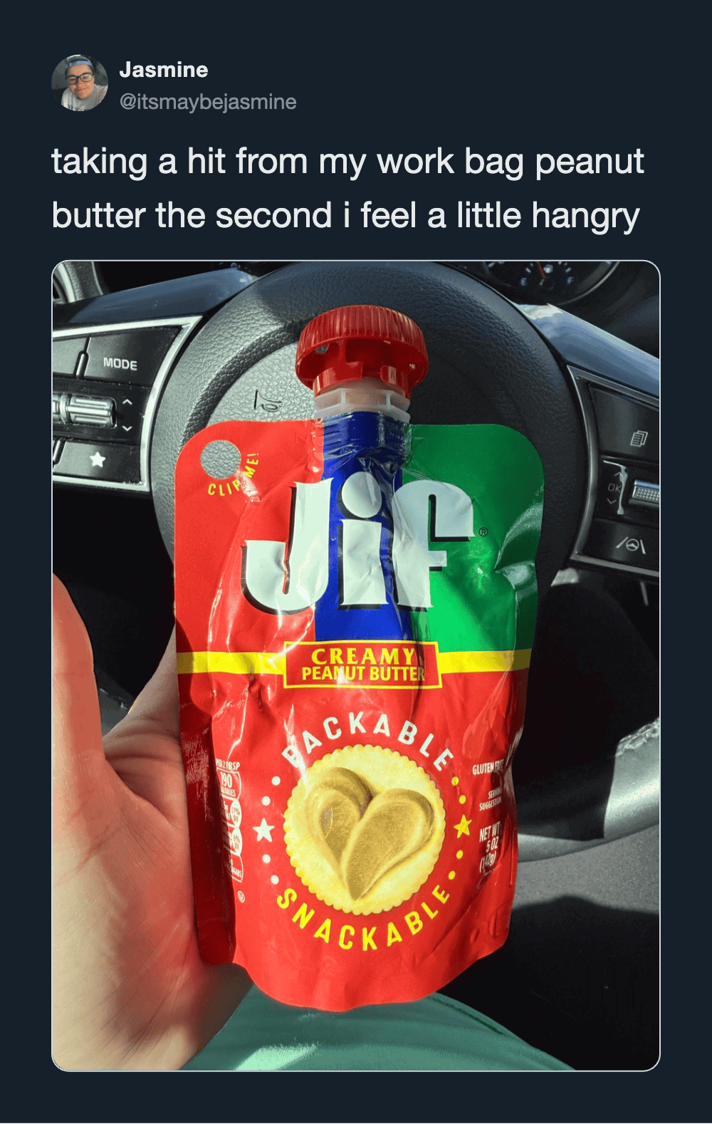 Jif peanut butter pouch with red cap, held in hand inside a car.