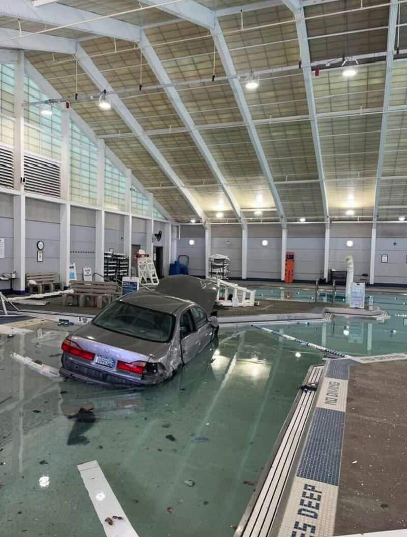 Car submerged in water inside an indoor swimming pool.